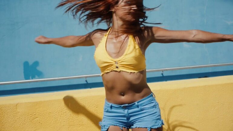 Woman dancing with vibrant energy in blue and yellow outfit.