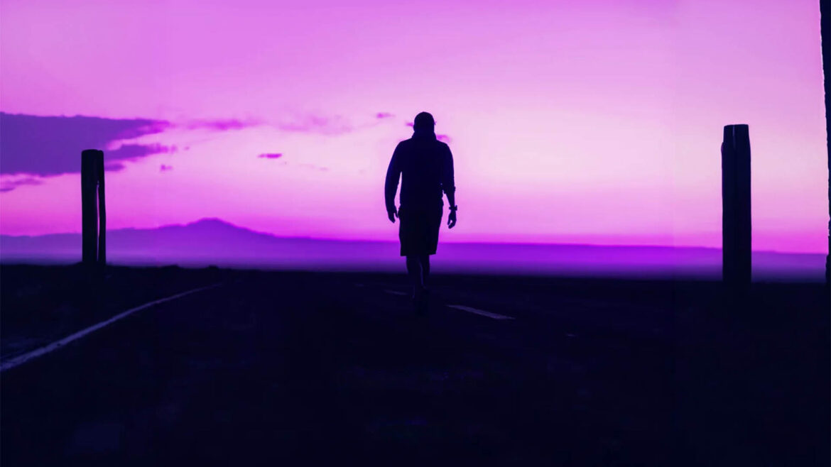 Silhouette of a person walking on a dark road at dusk with a vibrant purple sky, cover art for Soft Deep's Deeper Meaning