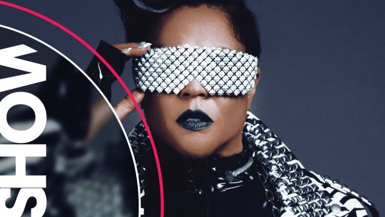 Crystal Waters wearing bold fashion with studded jacket and eye mask.